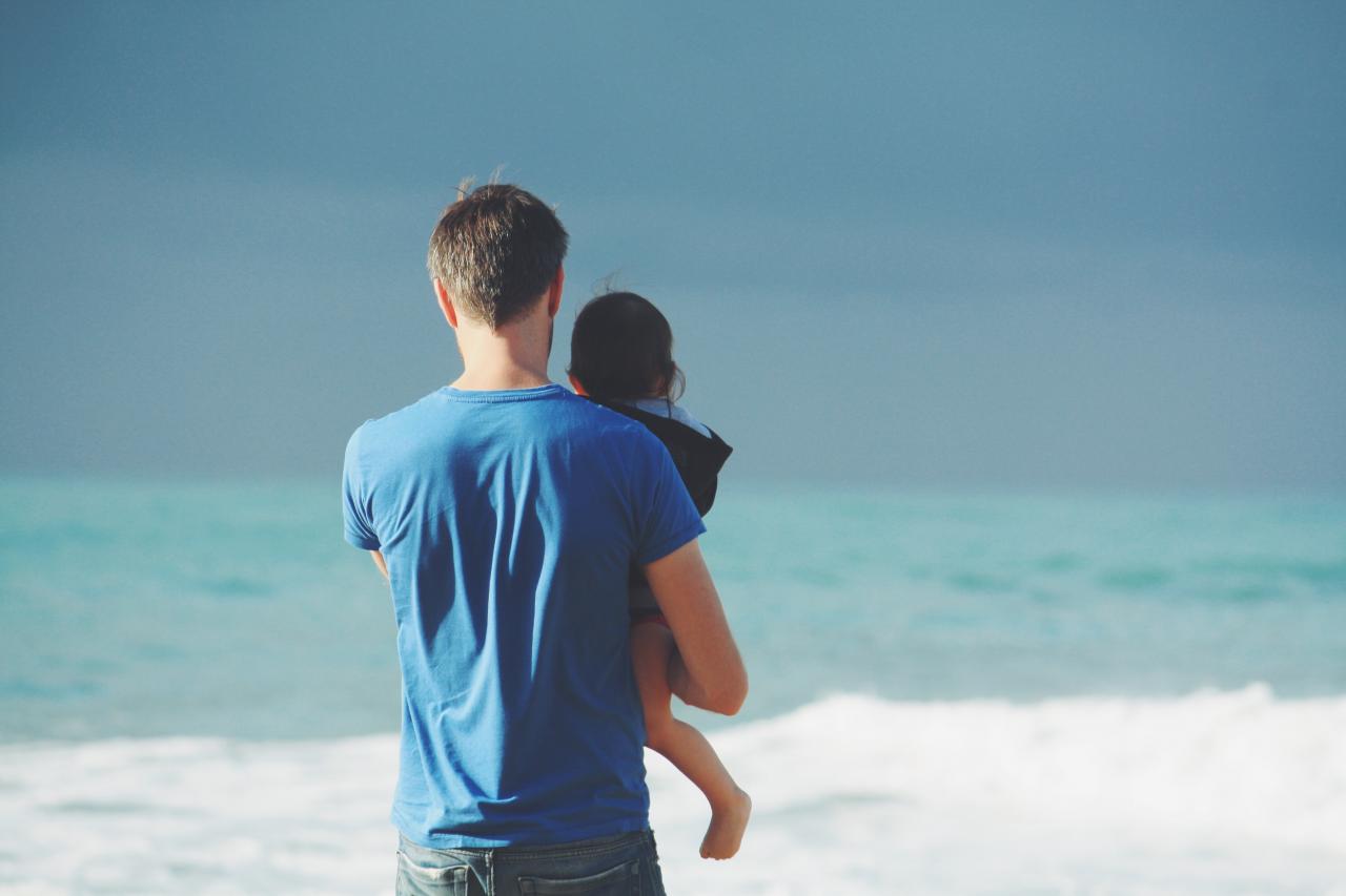 man holding his child at the beach