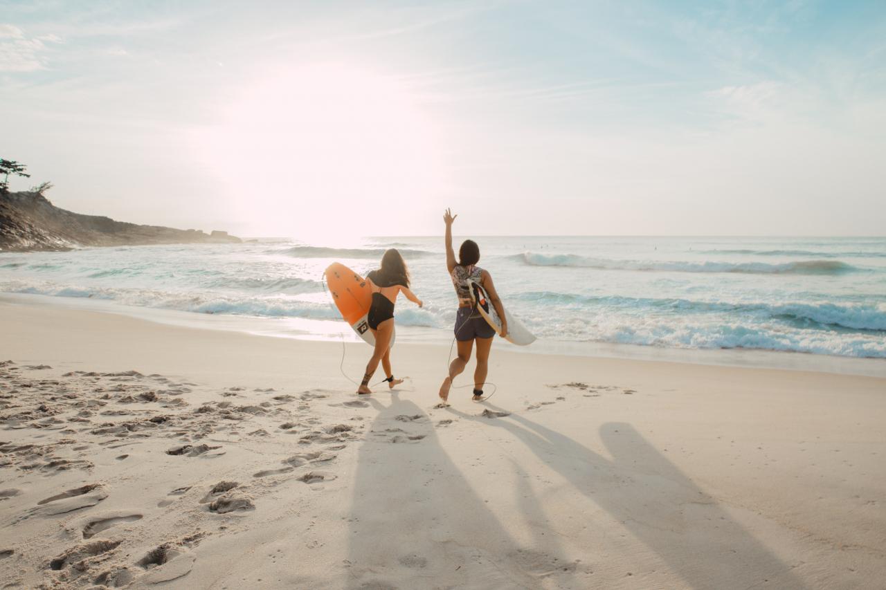 two surfers walking along the beach