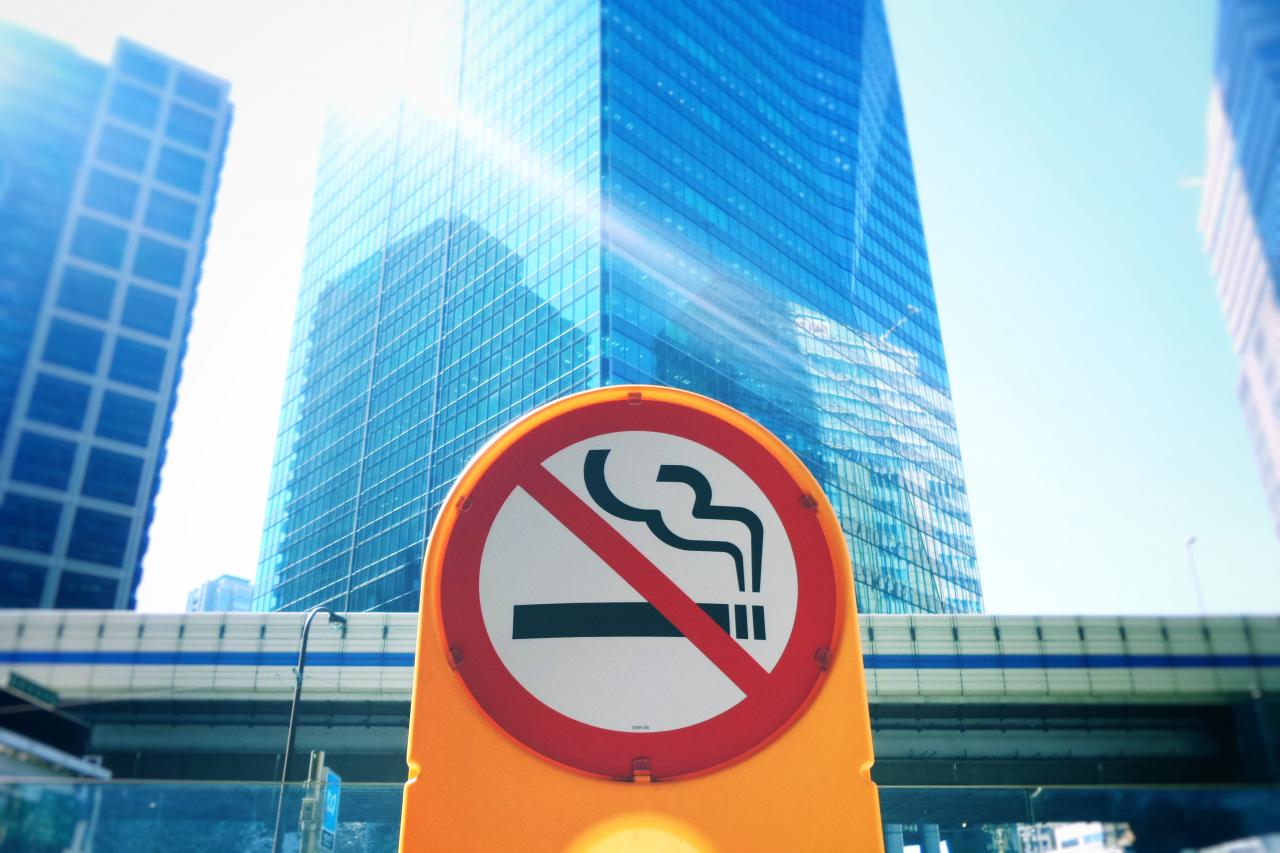 A street sign with a red circle and line over an image of a lit cigarette