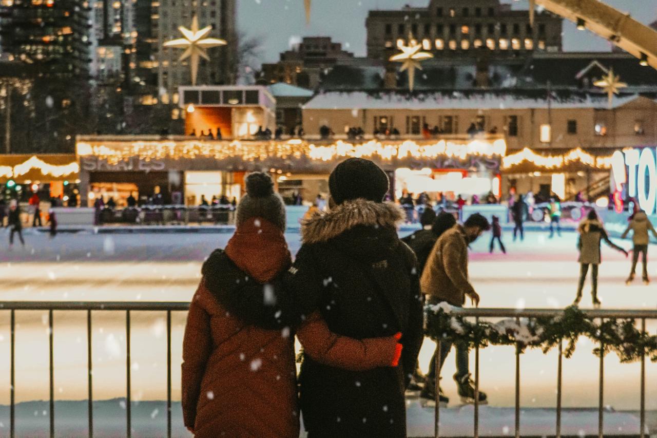 a couple looking out at a holiday decorated skating rink