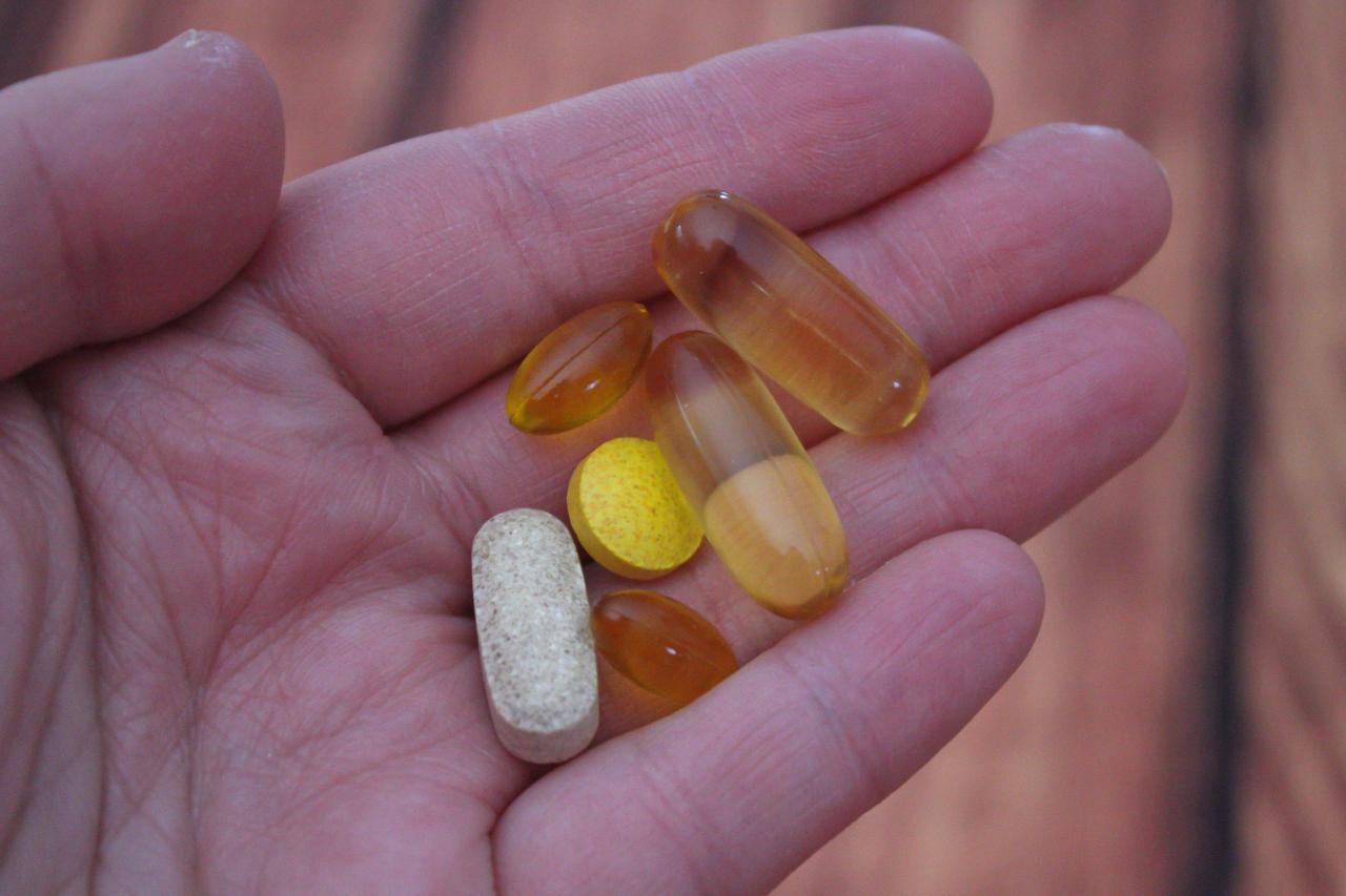 picture of a hand holding different pills and vitamins