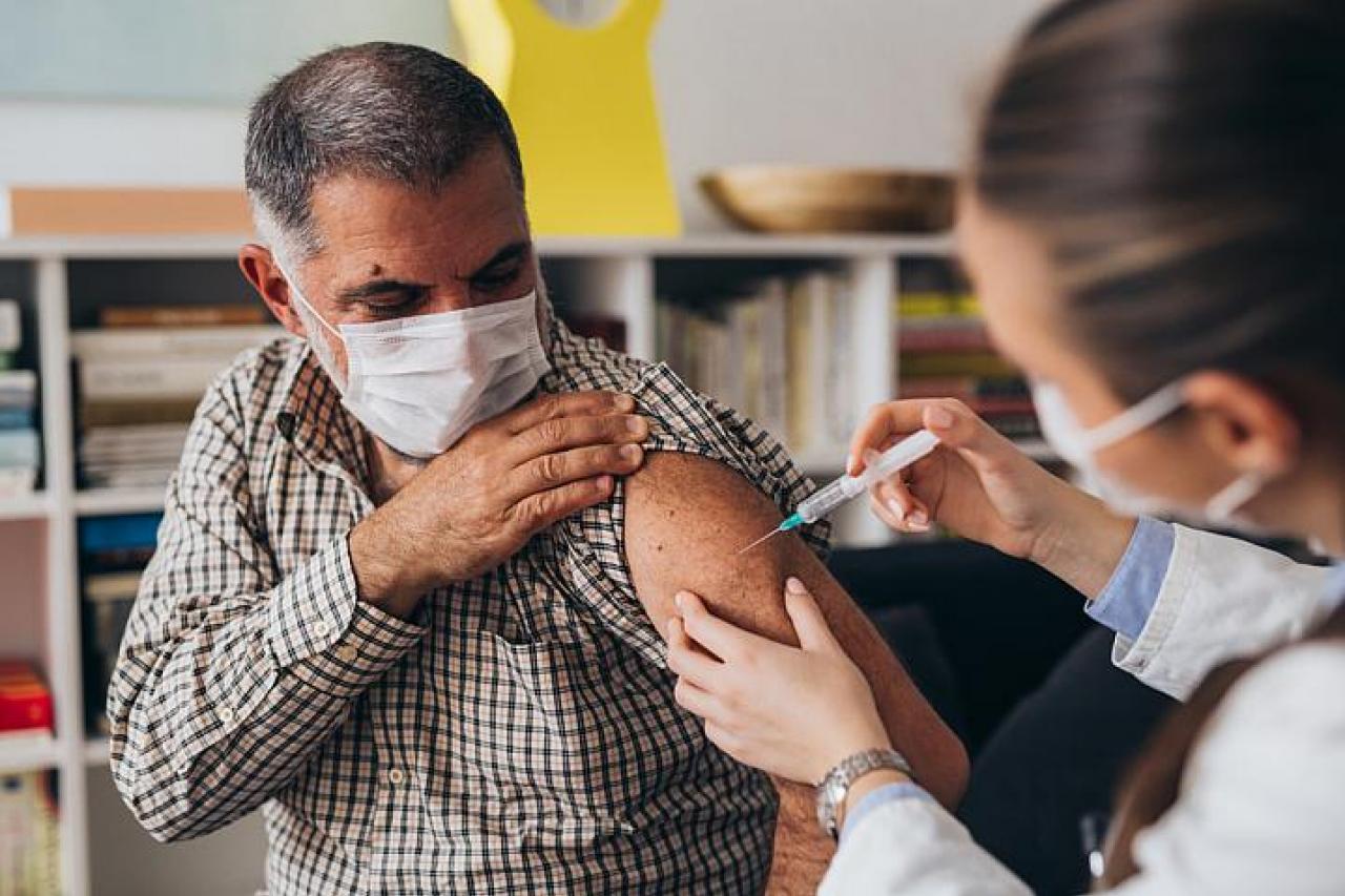 Person wearing a mask getting a COVID-19 vaccine from their health care provider