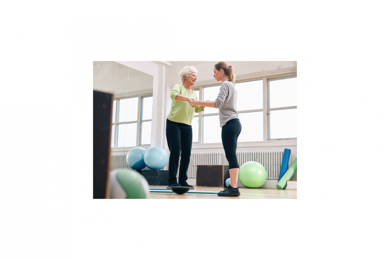 Female trainer helping senior adult woman in a gym exercising with a bosu balance training platform