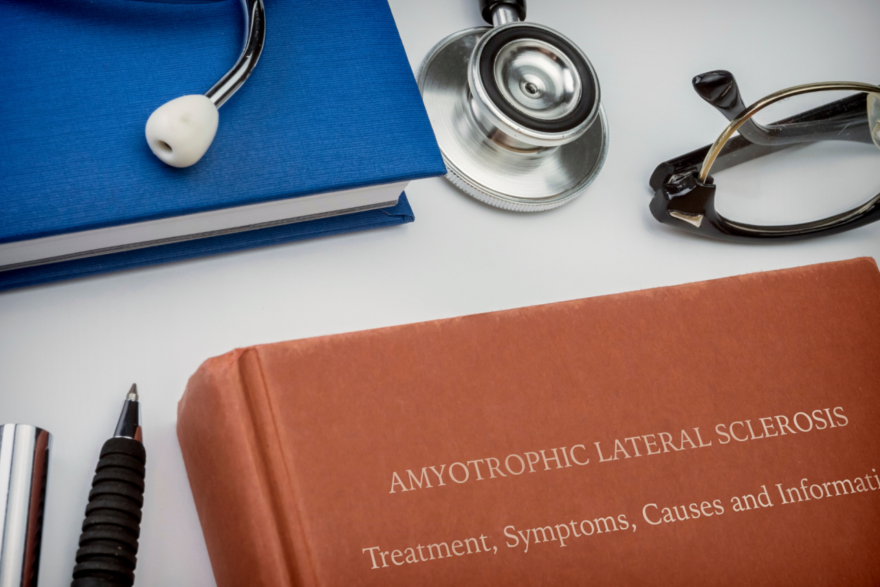 Conceptual image of a book entitled “Amyotrophic Lateral Sclerosis” alongside a stethoscope, eyeglasses, notebook, and writing utensils