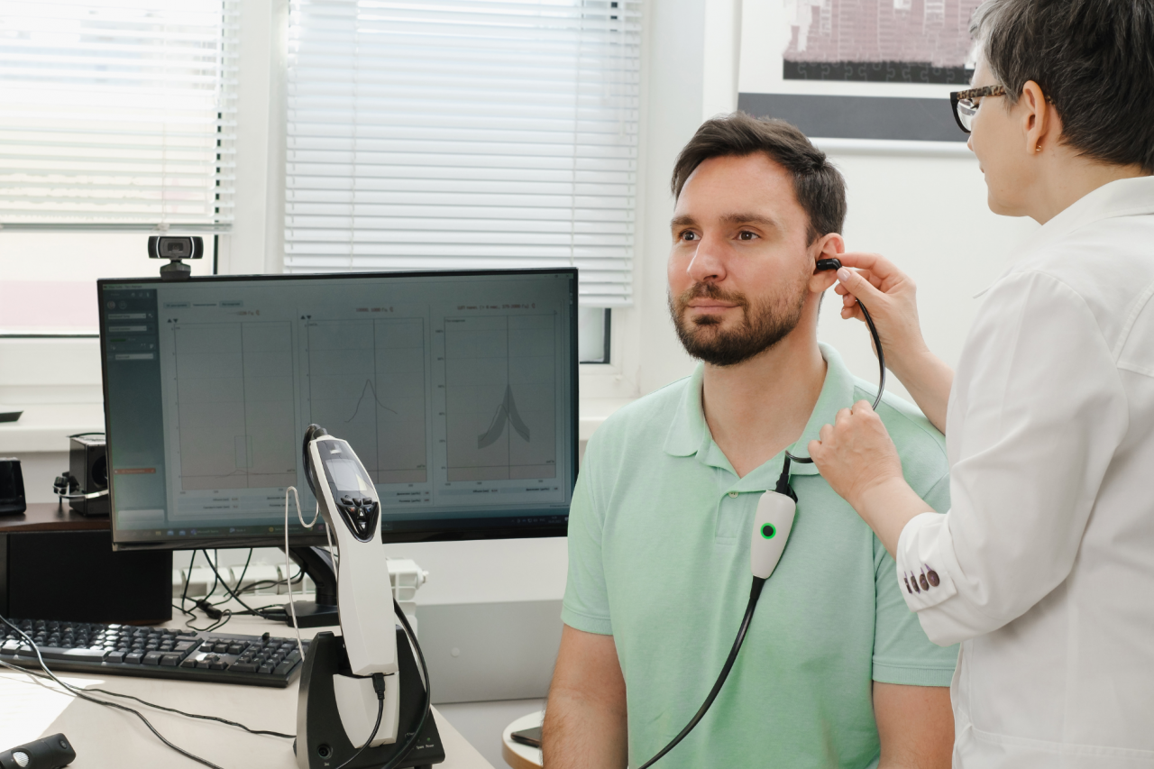 Audiologist performs a hearing exam on a middle-aged man