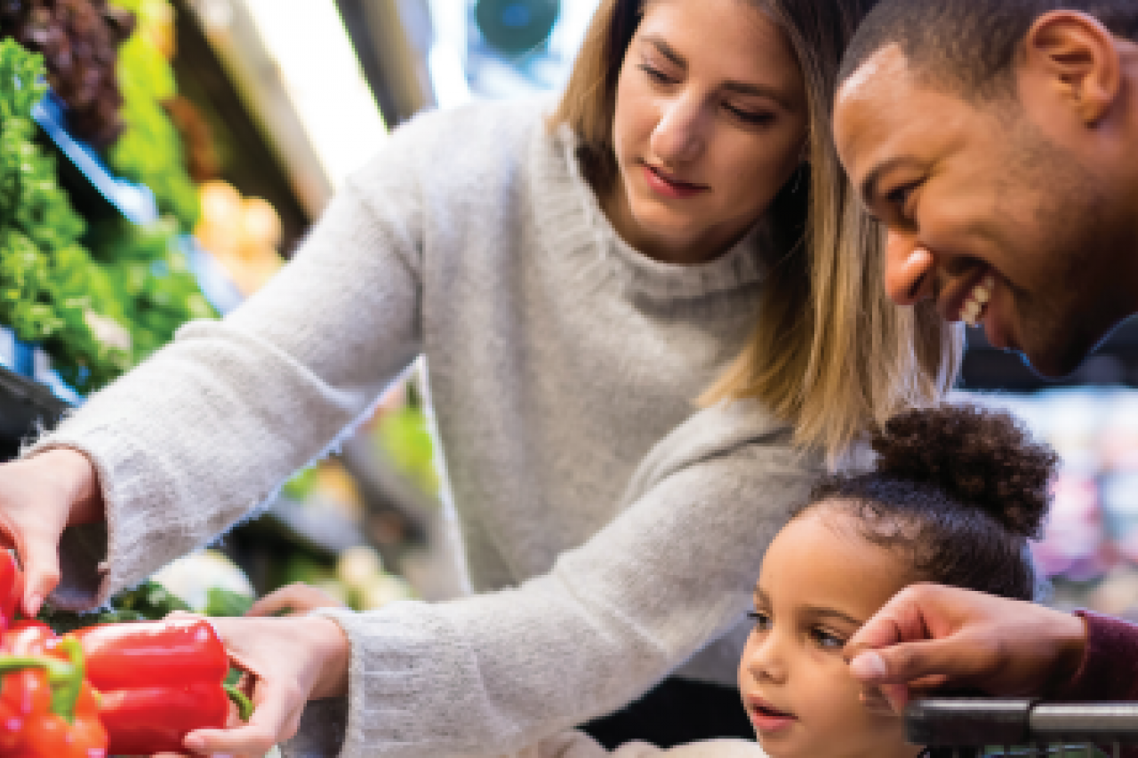two adults and a child at a supermarket looking at vegetables