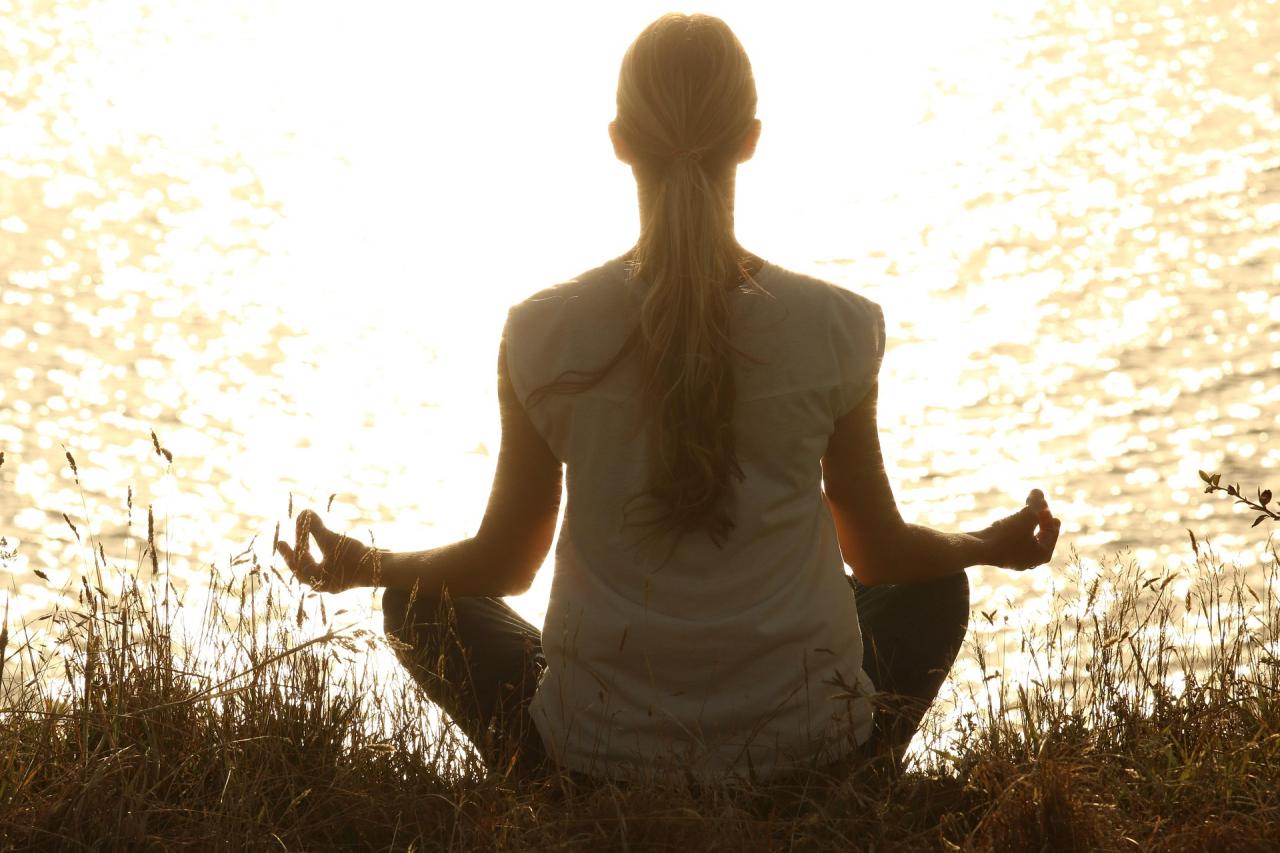 woman meditating in front of lake
