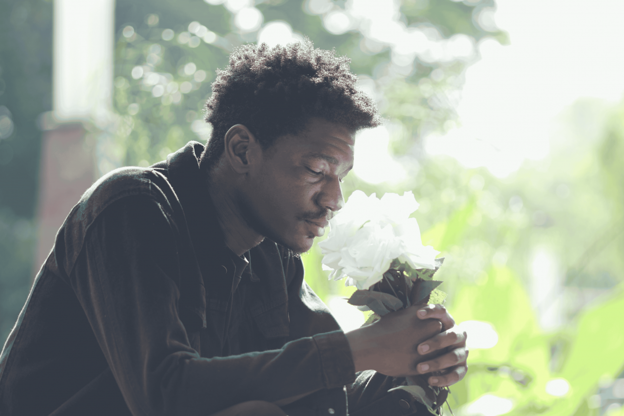 A man holding flowers grieving