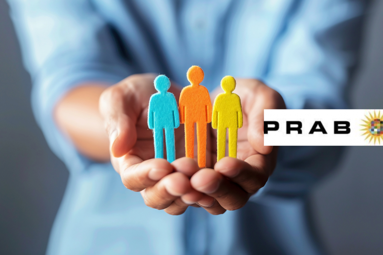 Hands stretched out holding paper cut-out of a family with the PRAB logo above