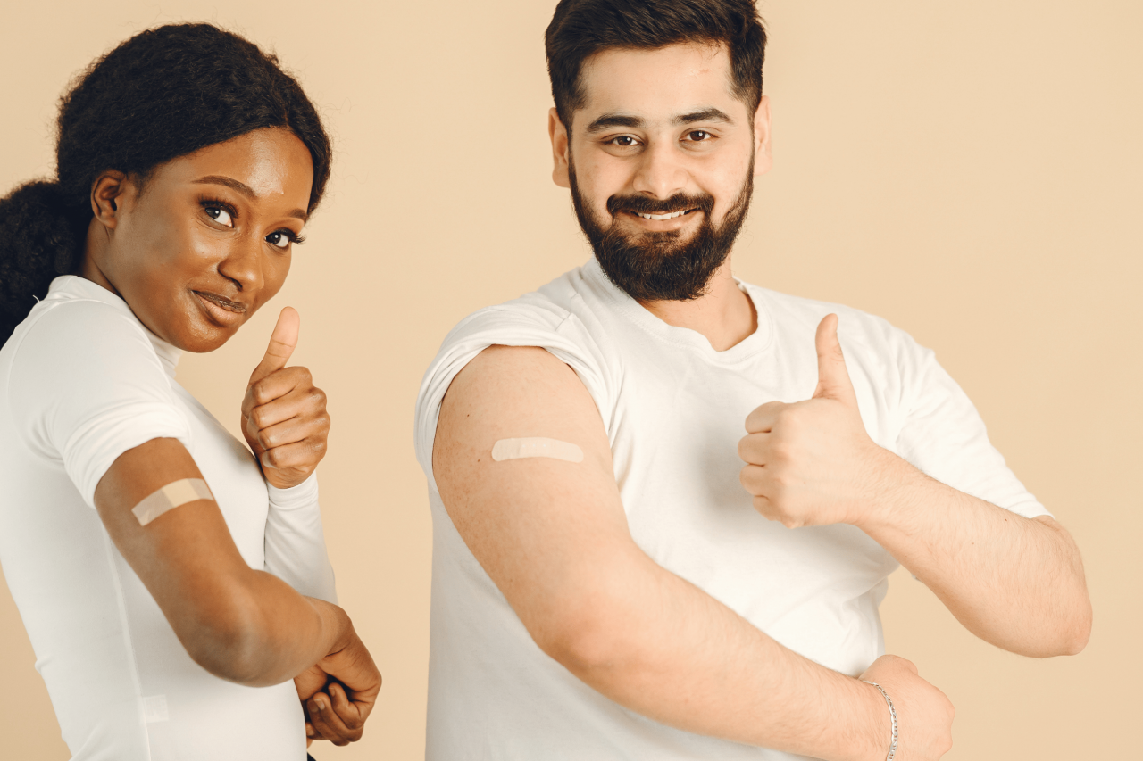 A young woman and a young man put a thumbs up after receiving a vaccine
