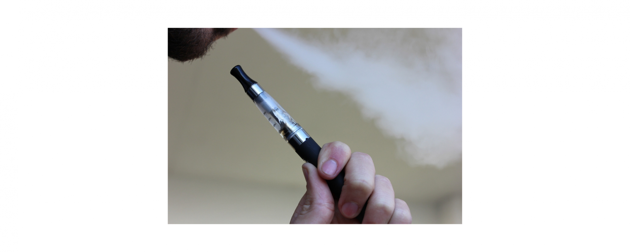 Person holding a vaping/e-cigarette pen while blowing out smoke from their mouth
