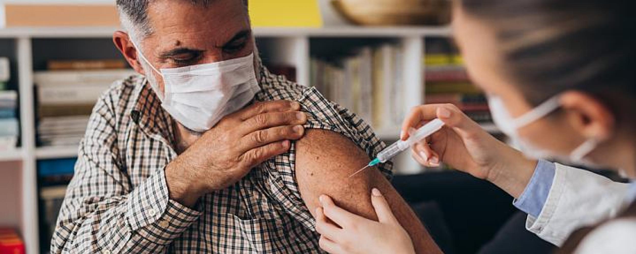 Person wearing a mask getting a COVID-19 vaccine from their health care provider