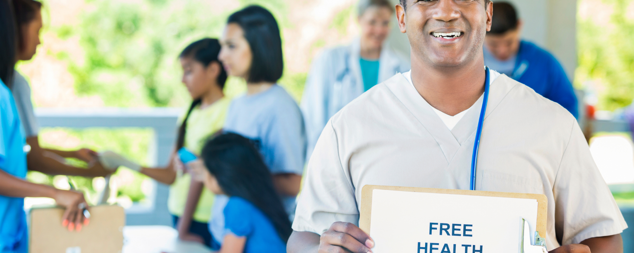 A healthcare professional holding a 'free health screenings' sign