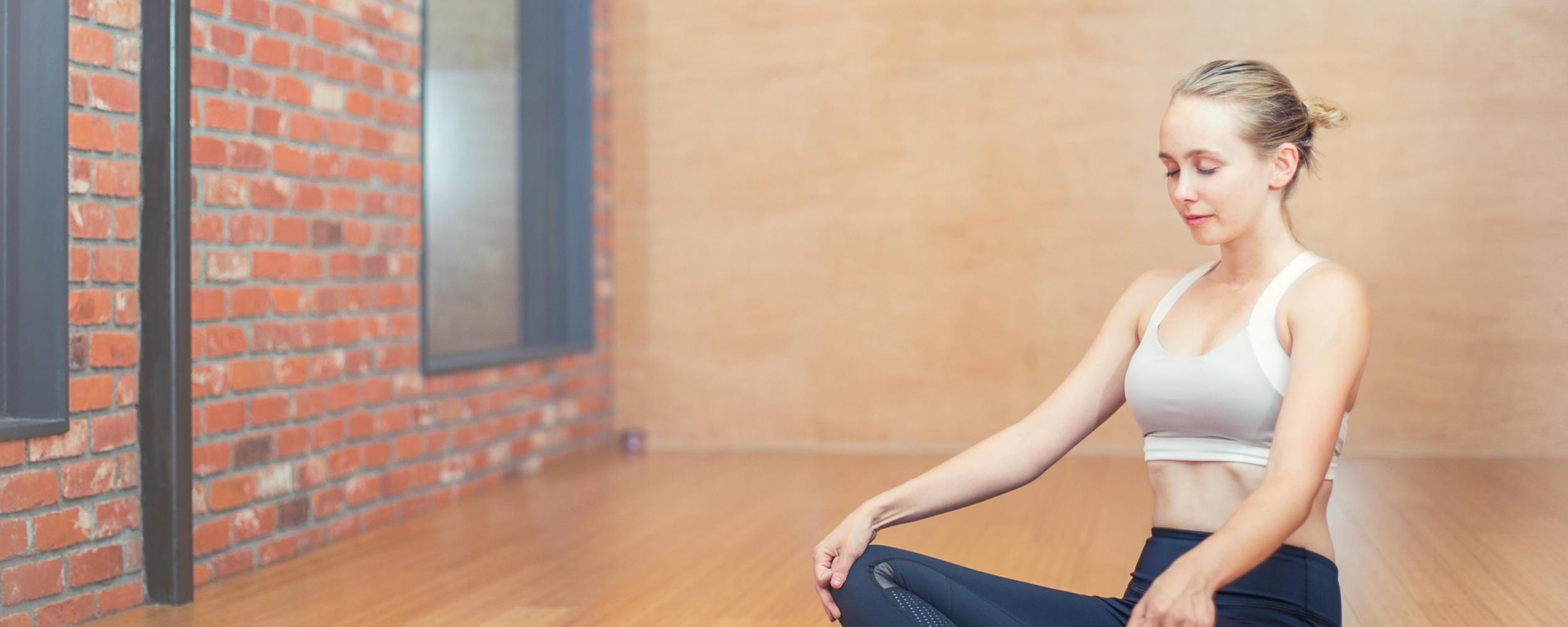 Woman sitting on yoga mat meditating