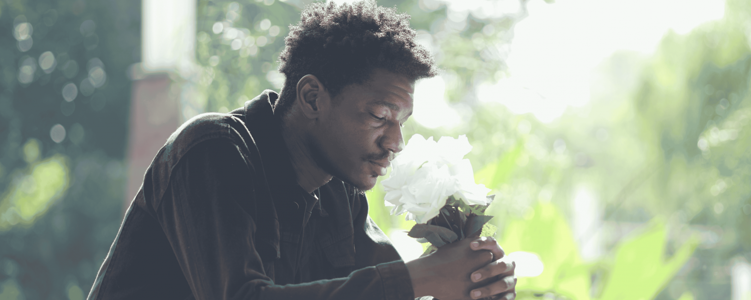 A man holding flowers grieving