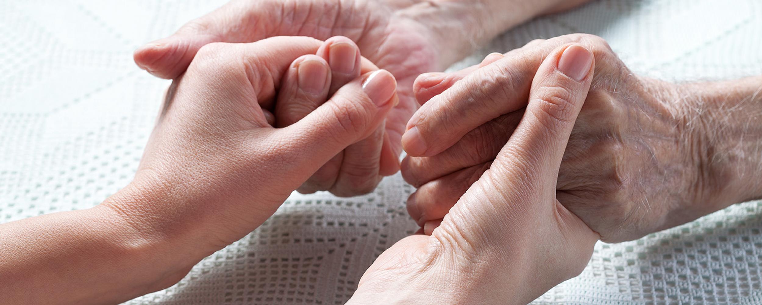 Two elderly people holding each other's hands