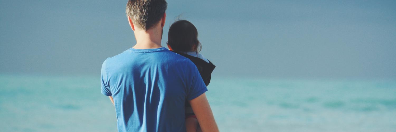 man holding his child at the beach