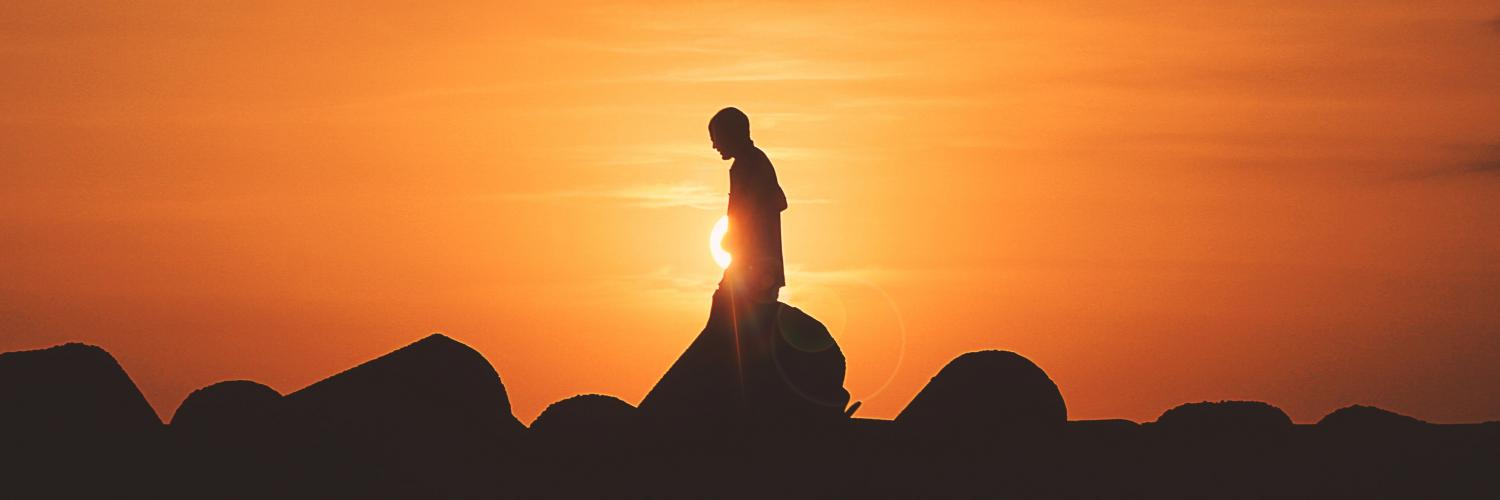 person walking alone during sunset