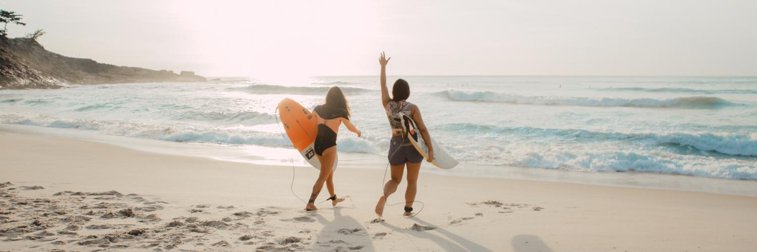 two surfers walking along the beach