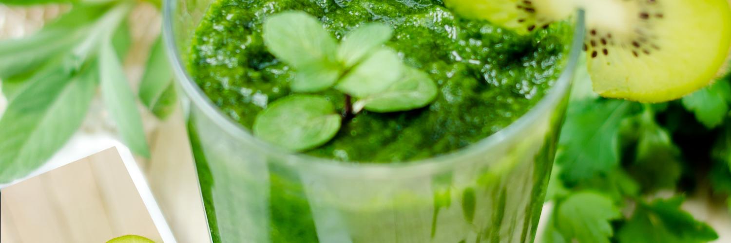 a picture of a green smoothie consisting of kiwi; parsley; mint; and orange