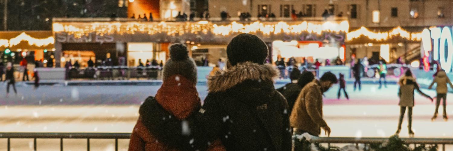 a couple looking out at a holiday decorated skating rink