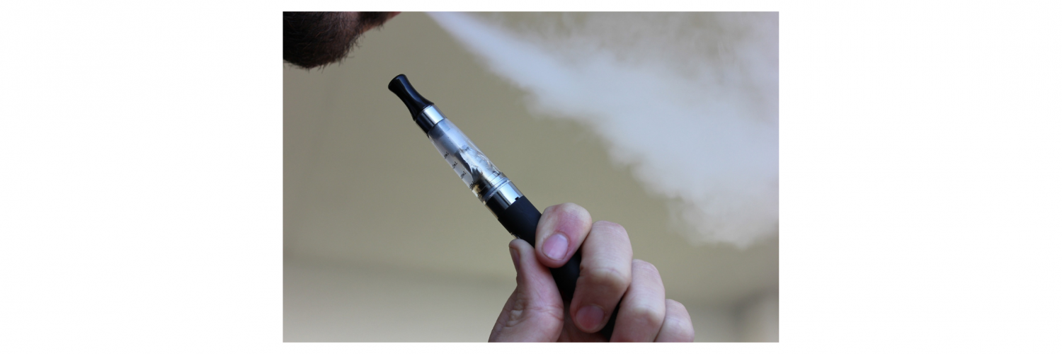 Person holding a vaping/e-cigarette pen while blowing out smoke from their mouth