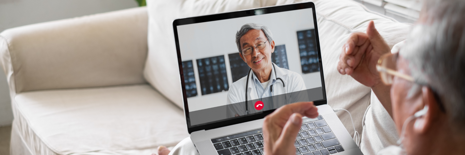 Elderly man having a telemedicine/telehealth video call with his healthcare provider using his laptop at home on his couch