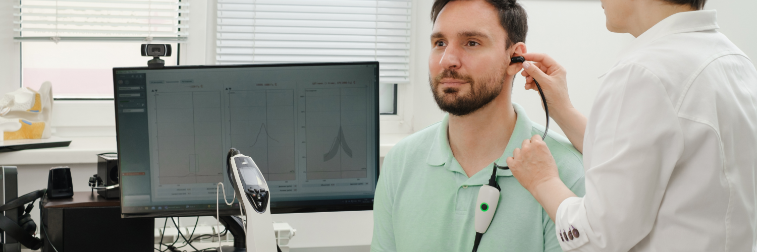 Audiologist performs a hearing exam on a middle-aged man