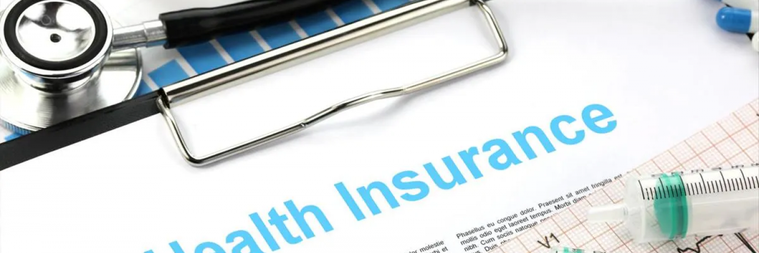 "health insurance" written at top of paper on clipboard surrounded by stethoscope and other medical instruments