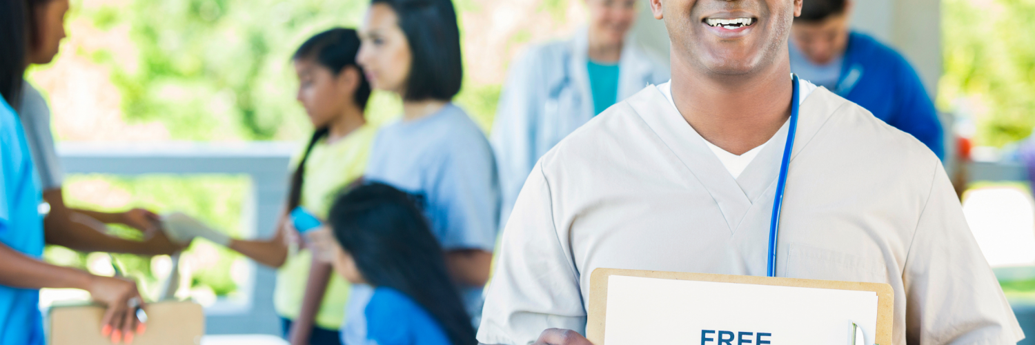 A healthcare professional holding a 'free health screenings' sign