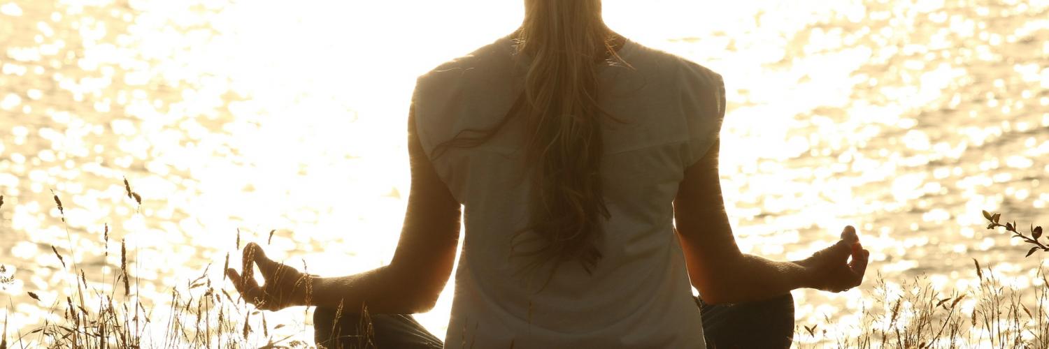 woman meditating in front of lake
