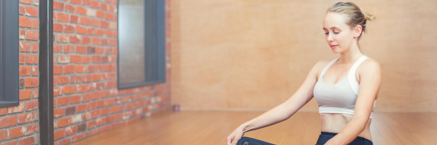 Woman sitting on yoga mat meditating