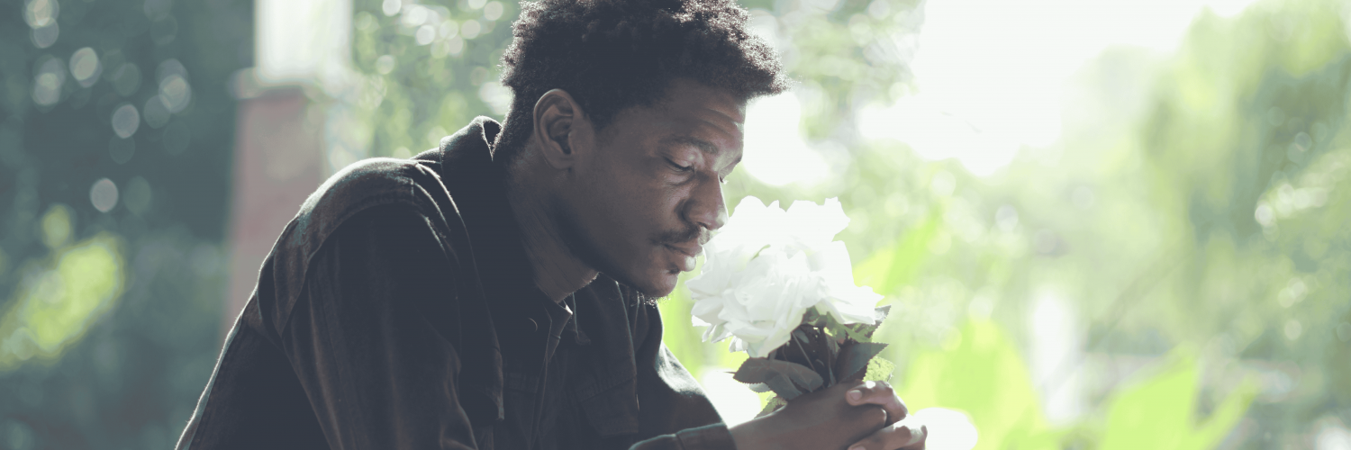 A man holding flowers grieving